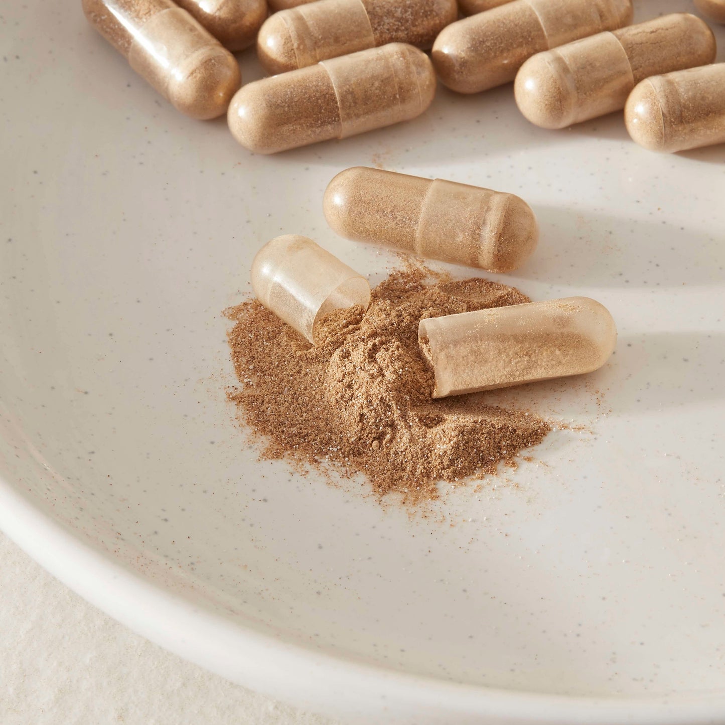vegan functional muchroom capsule open with powder supplement on a white plate