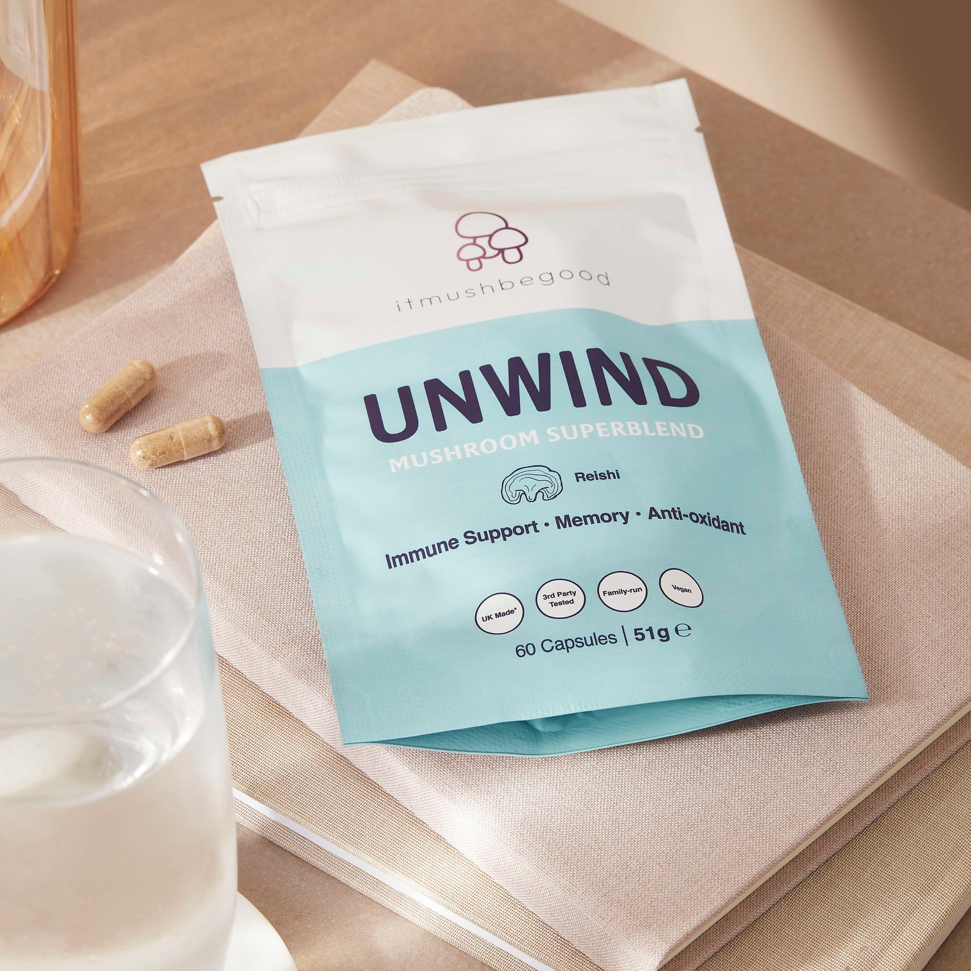 unwind packaging on a notebook next to a glass of water with tablets next to it.