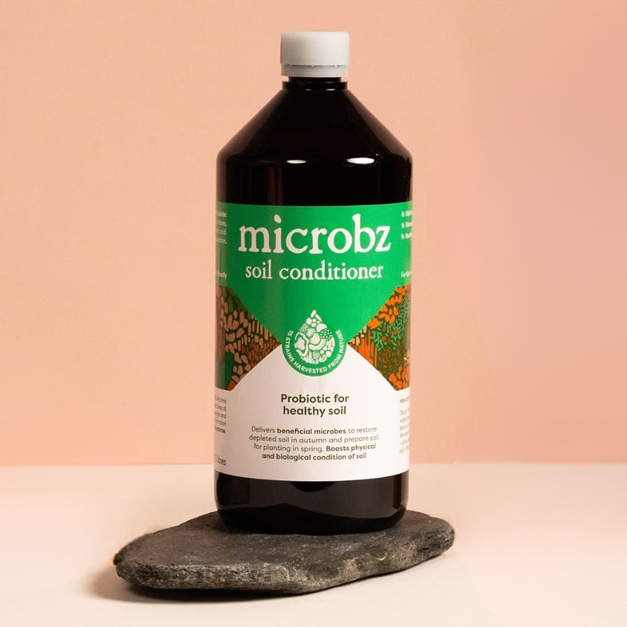 Bottle of microbz soil conditioner on a stone surface with a peach background